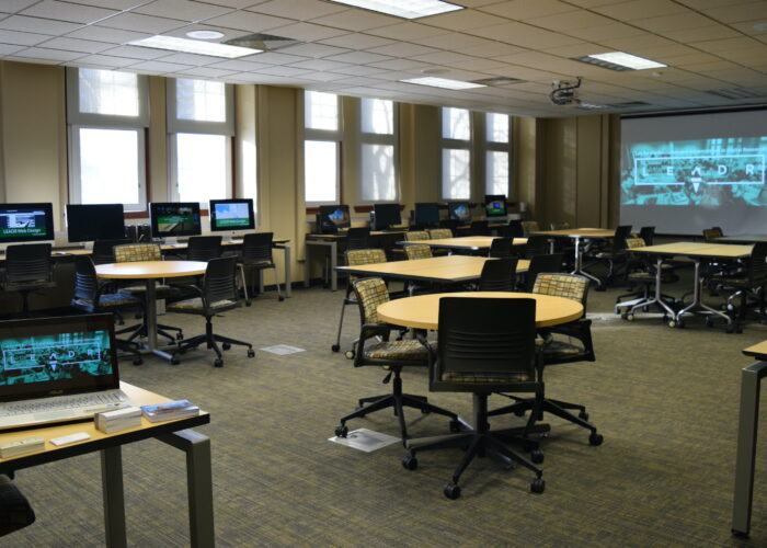 A classroom with many computer monitors reading LEADR sits empty, awaiting students.