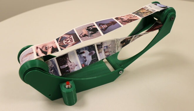 Final 3D-printed version of the Möbius Machine. Green plastic allows a canvas strip of instagram feeds to pass through in an infinite loop on a spindle.