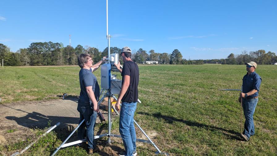 From left, Andrew Balmos, Josh Bailey and Derek Hurley install a device to the top of their SPRING tripod. This system collects data from sensors placed across a field to help farmers and researchers review real-time data from their fields or orchards for management decision-making (Photo provided by Purdue University/IoT4Ag).