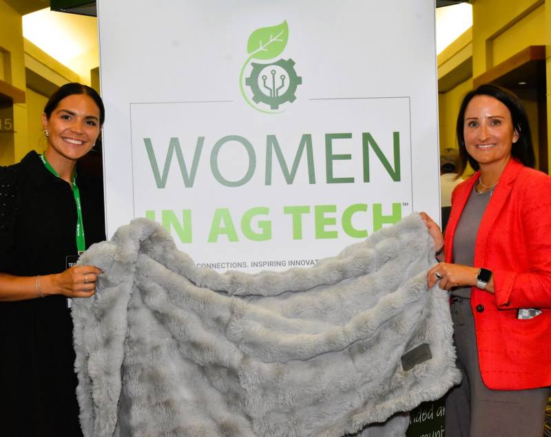 Kelly Miller and Courtney Zimmerman of Agri-Access display one of the blankets they gave attendees at the WiAT meeting.