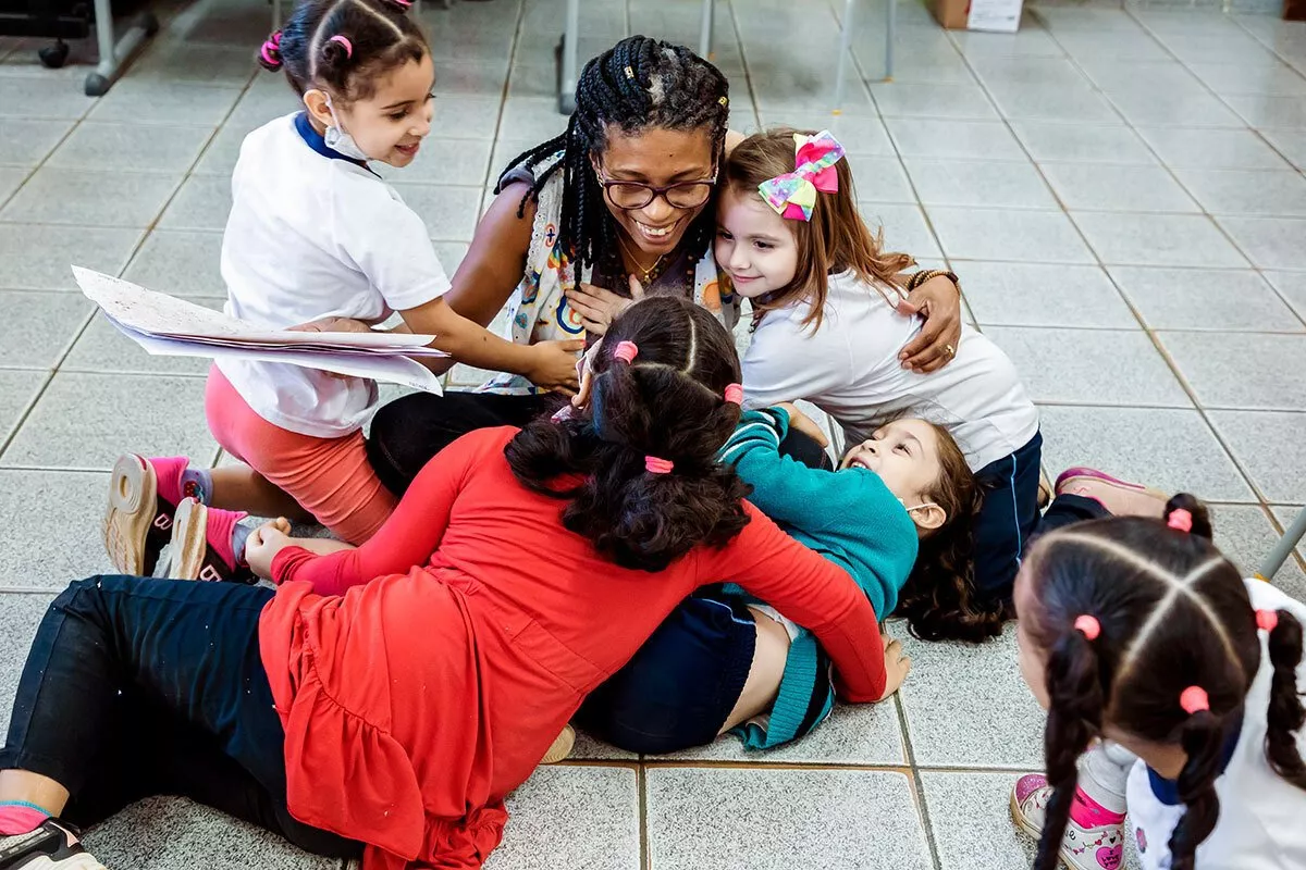 professora e crianças se abraçando