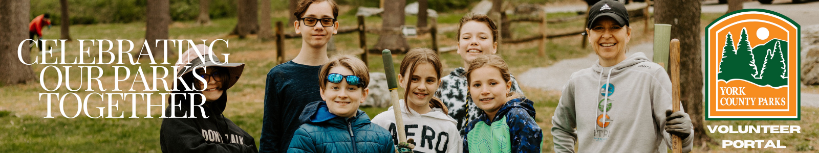 Image shows a family at a volunteer event outdoors holding shovels and wearing work gloves. 