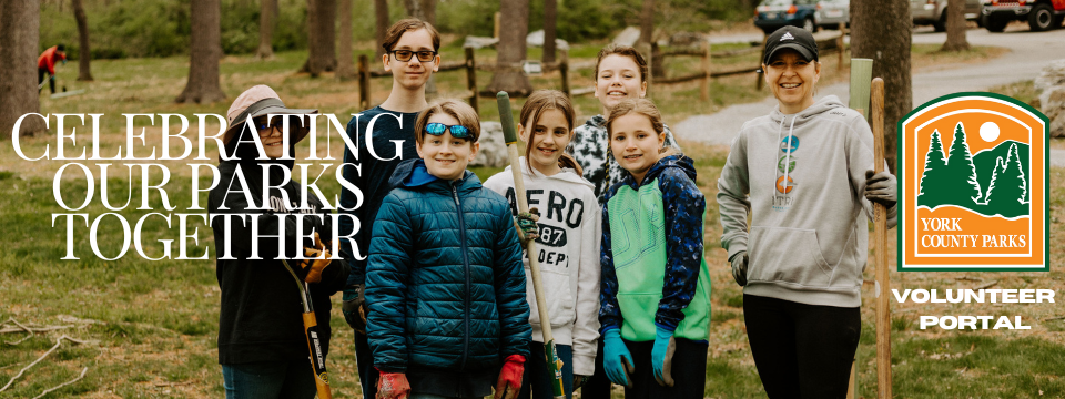 Image shows a family at a volunteer event outdoors holding shovels and wearing work gloves. 