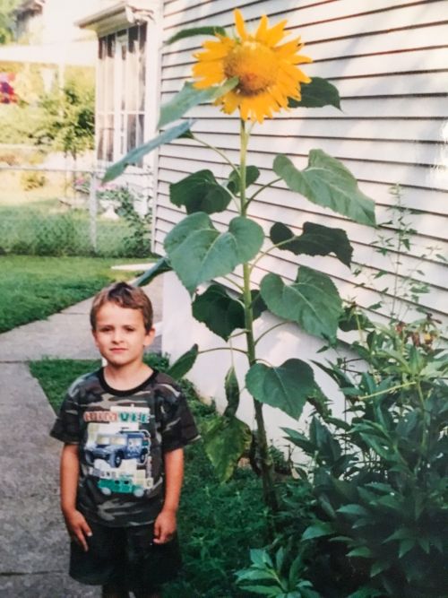 At four years old in 1998, I stood next to the sunflower I grew from seed. It was one of my earliest experiences growing a plant — and one I still remember today.