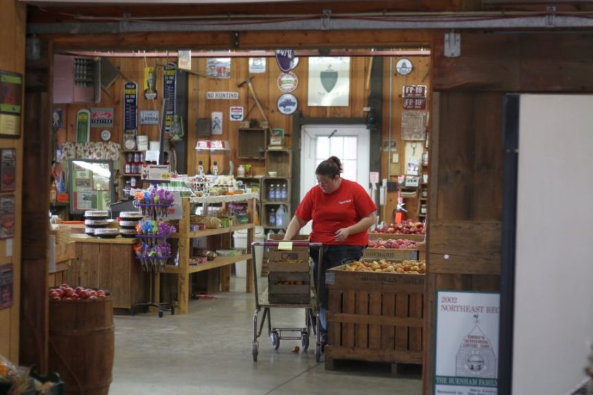 An employee restocks pears.