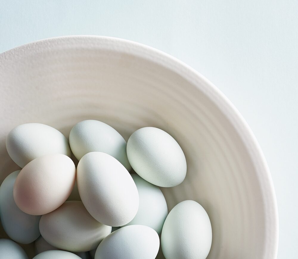 Multi-colored pastel eggs rest in a bowl
