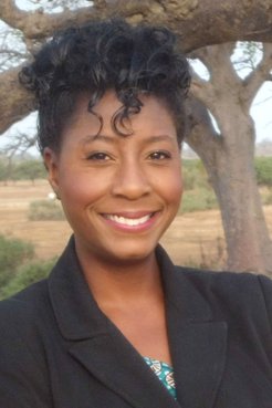 Black Woman Volunteer in formal dress smiles for the camera in Senegal.