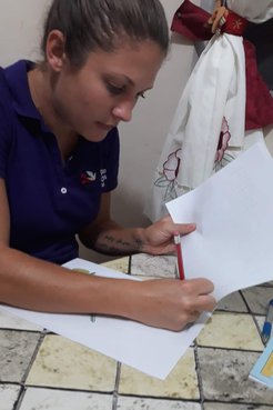One person sitting down writing and looking at paper