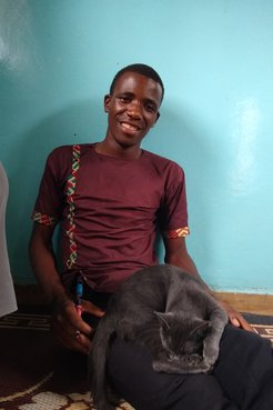A young man leans against the wall studying a booklet of lessons