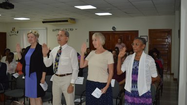 Four people standing up with right hand up