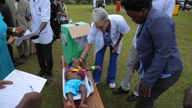 GHSP Volunteer, Janet examining a little child at teh camp.JPG