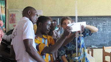 Teacher and student in front of white board conducting science experiment
