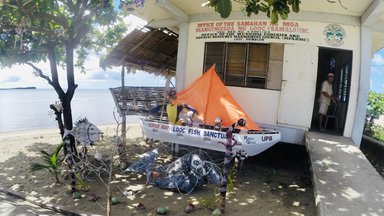 A little boat in front of a building on the beach- the Looc Fish Sanctuary