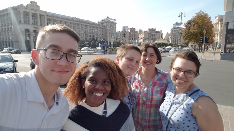 A group of people smile for a selfie on the streets of Ukraine.