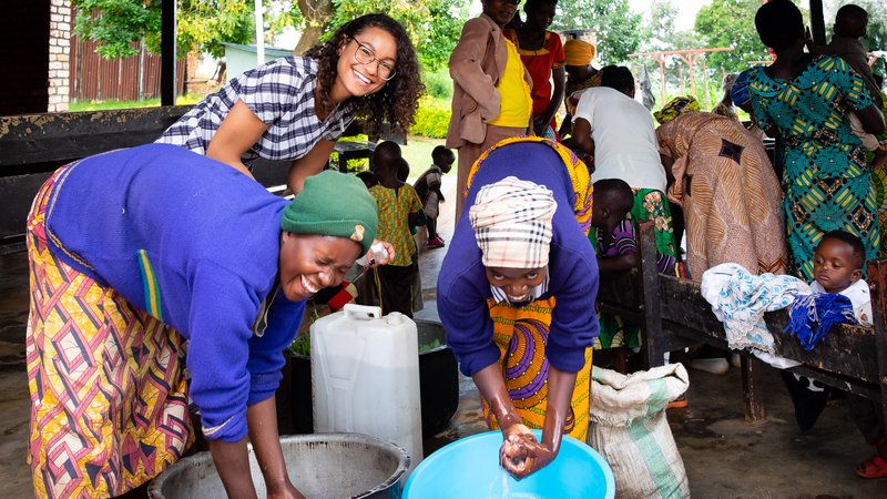 PCV Maya and two mothers wash their hands before preparing the group meal