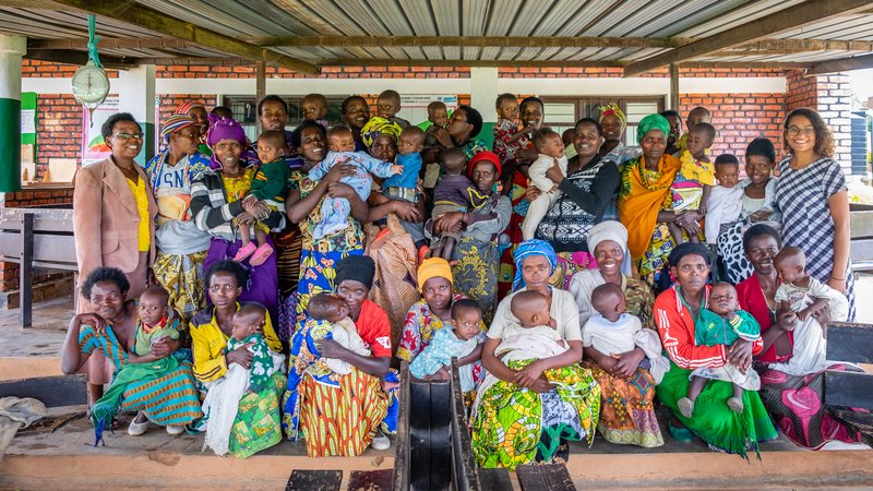 Group photo of mothers with babies, PCV Maya, and counterpart Gaudence