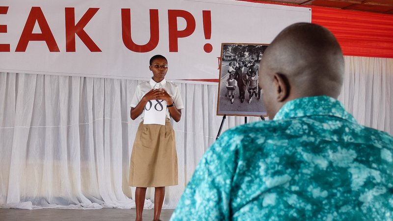 A student stands on the stage and delivers a speech.