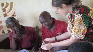 Two people sitting down and one person teaching them