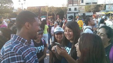 Group of students standing in front of individual with cell phone pointed at mouth