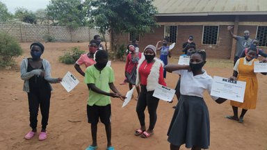 Youth in school uniforms proudly hold their GRS completion certificates