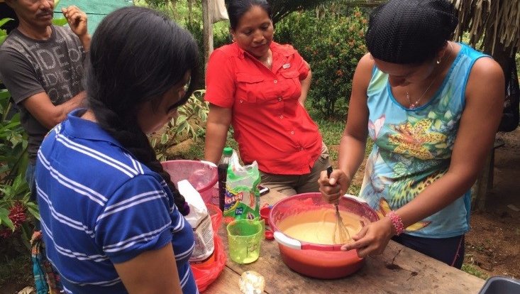 A woman uses in a whisk in bowl while baking outside