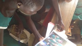 Girls in Ghana look at a picture of their Girl Scout pen pals in California.
