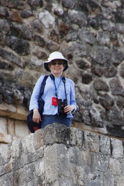 Carolyn standing near the top of a Mayan pyramid at Uxmal enjoying views of Green Jays and an Altamira Oriole.