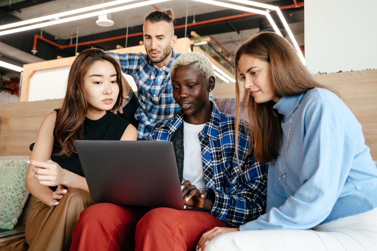 group of coworkers gathered around a laptop