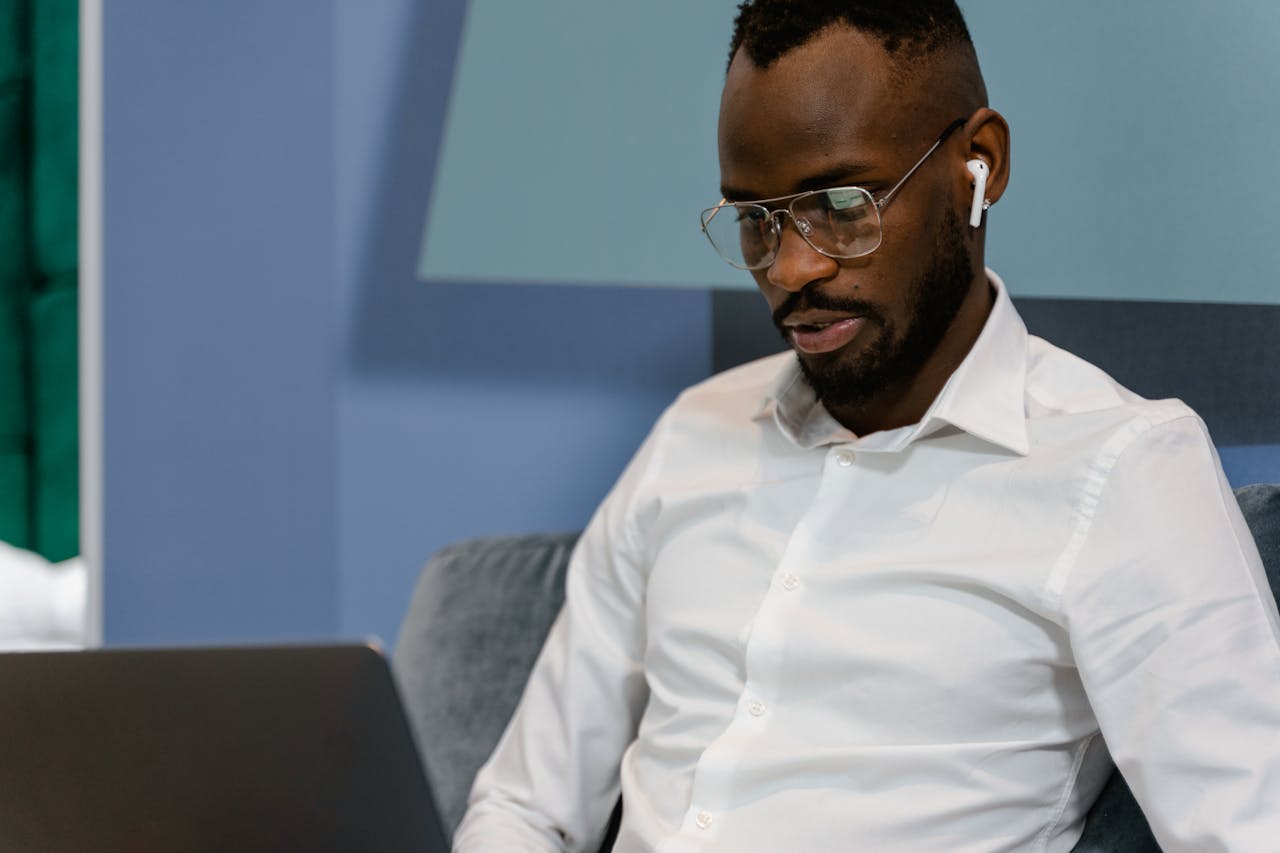 Professional man using a laptop with earbuds in, representing digital engagement for associations.