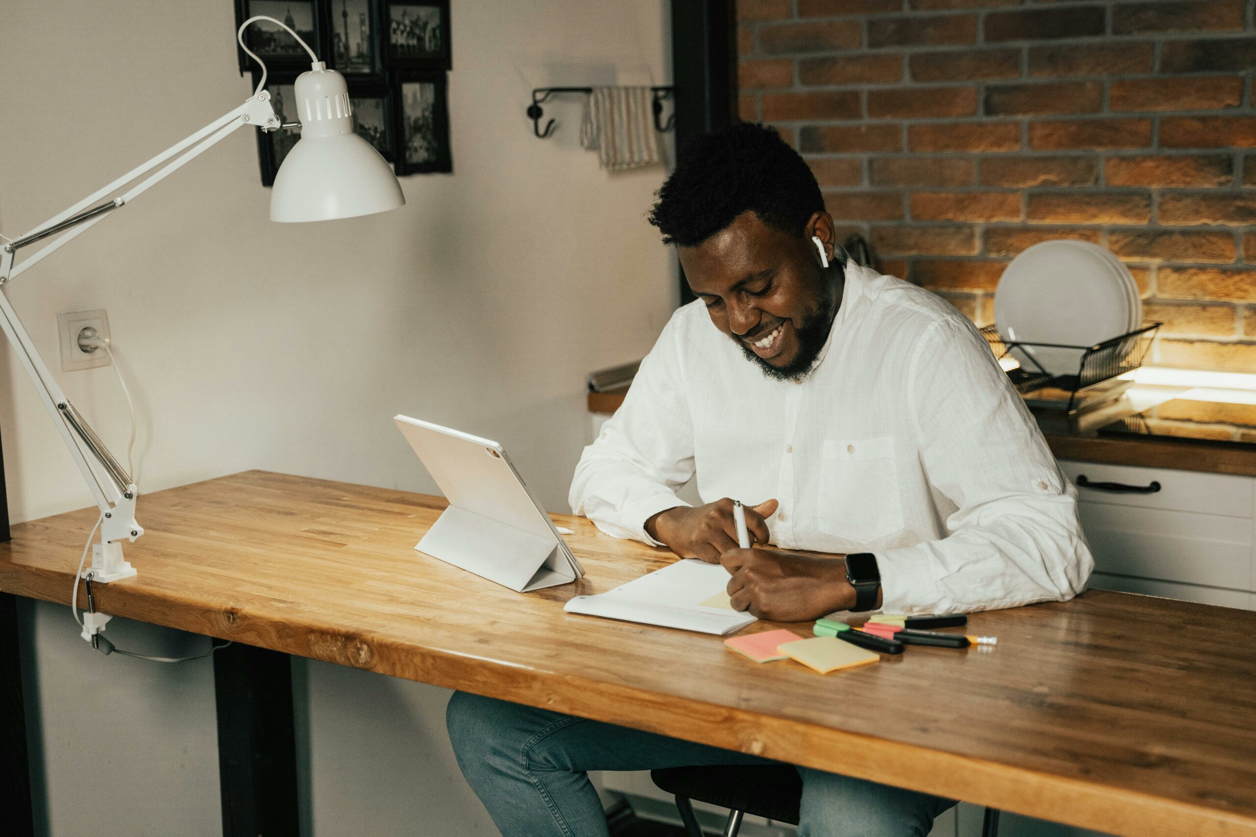 Professional writing notes while learning from a tablet at a modern workspace.