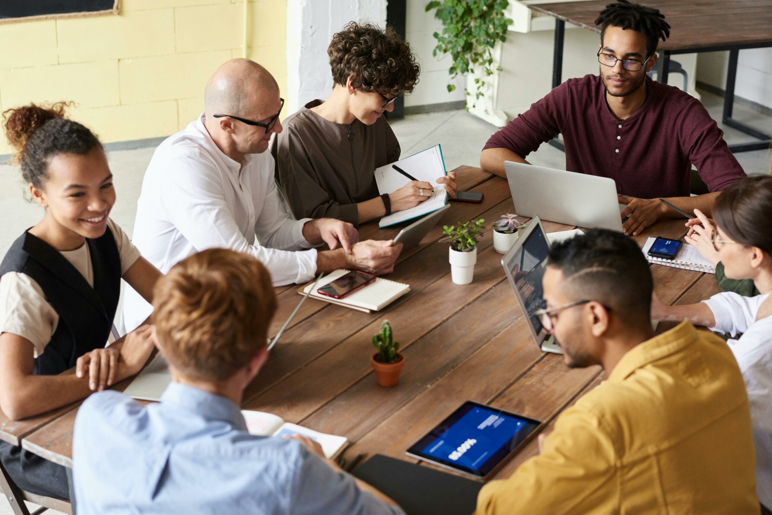 Group of diverse professionals collaborating around a table with laptops and notes, representing strategic revenue-sharing partnerships for associations.
