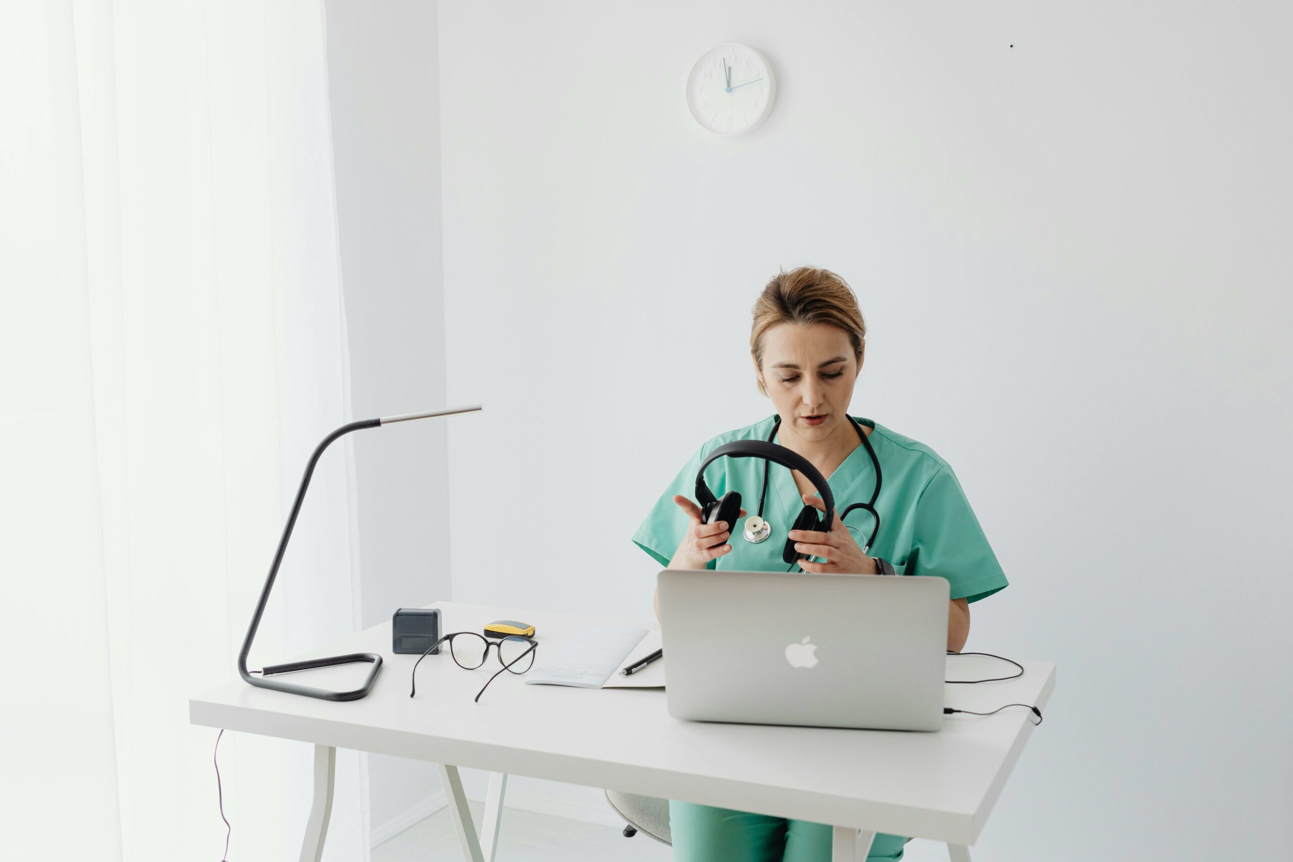 Medical professional in scrubs putting on headphones, preparing for online microlearning session.