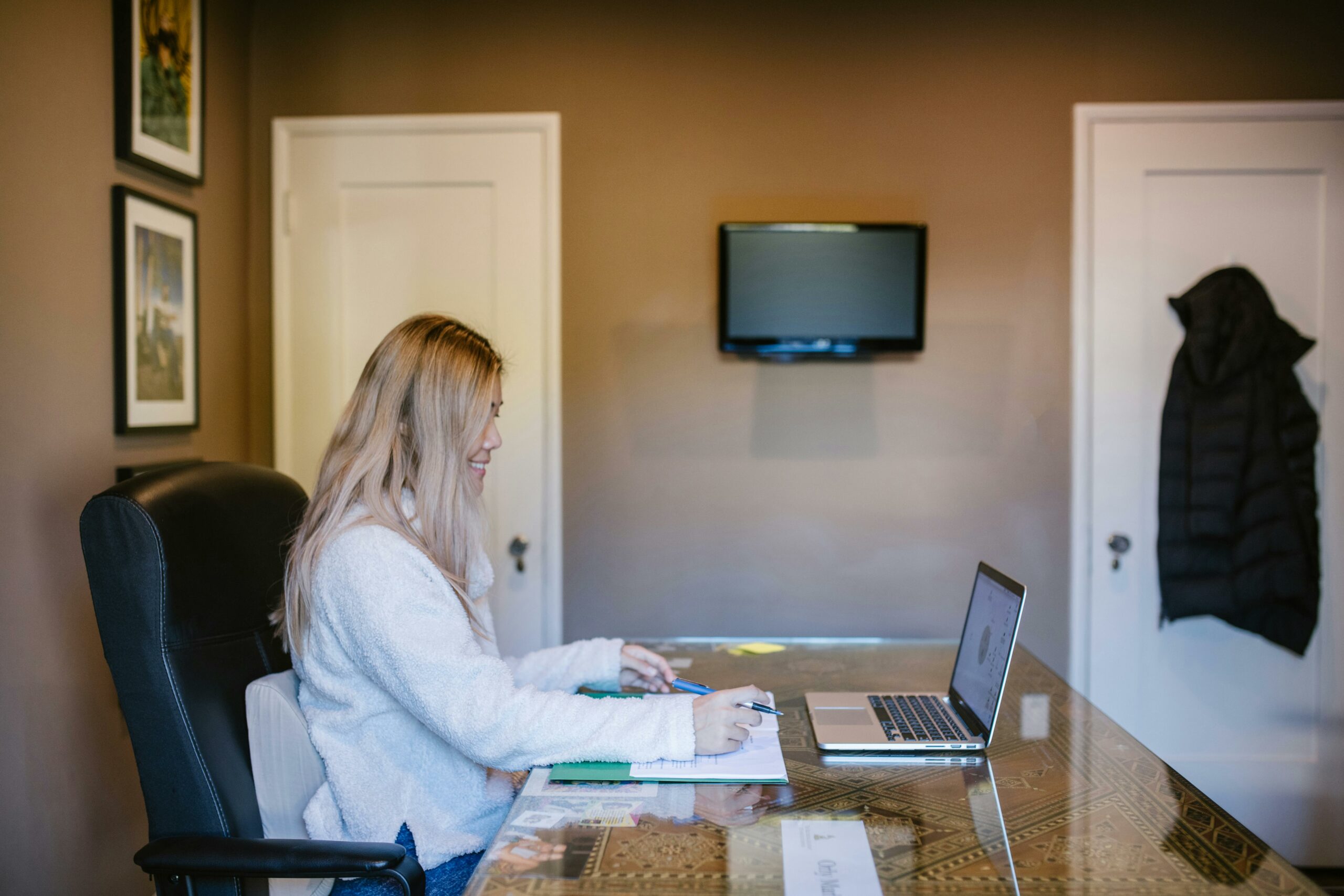 A woman sits at a desk working on a laptop and taking notes, representing online learning and professional development for associations.