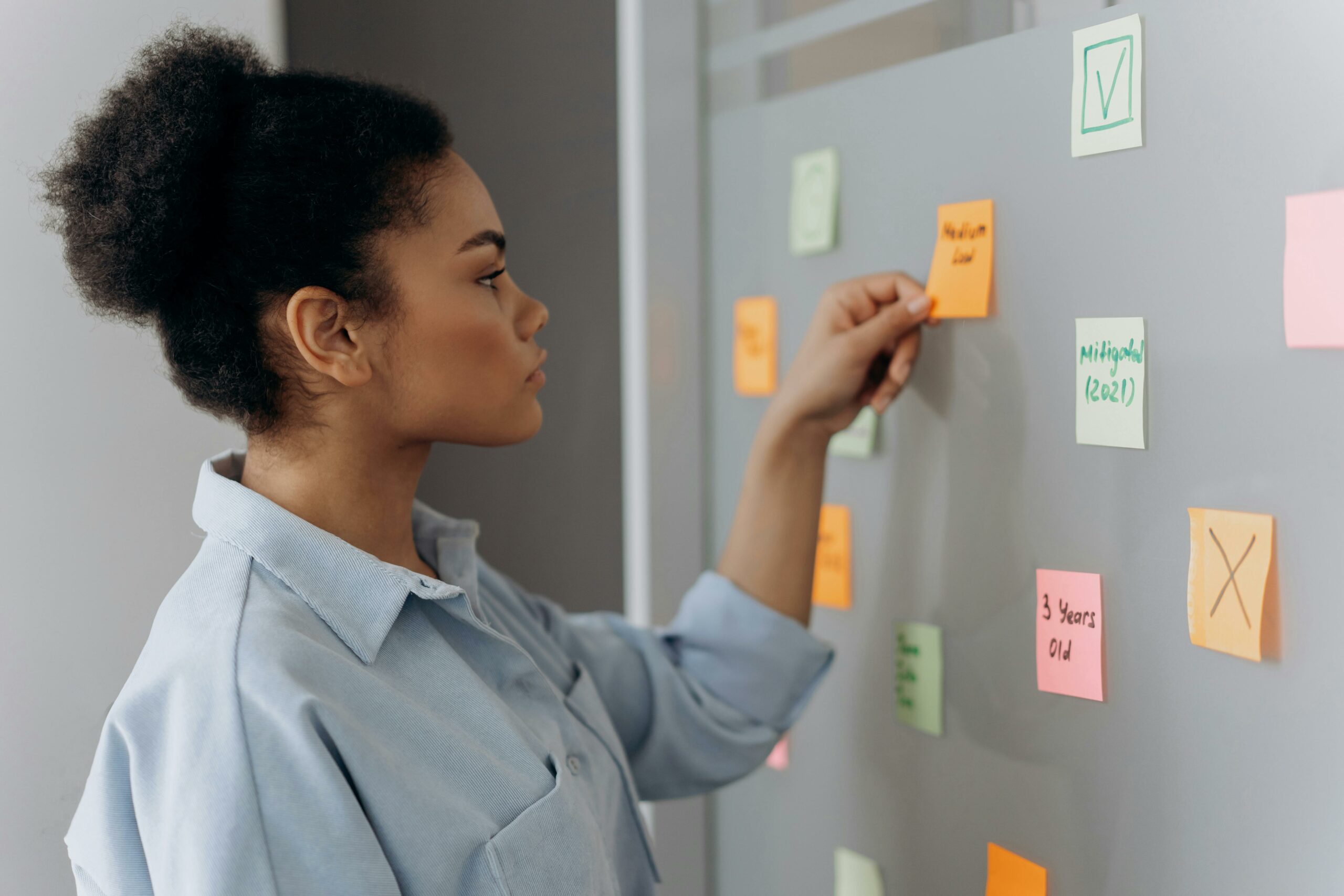Woman organizing colorful sticky notes on a wall while planning content strategies.