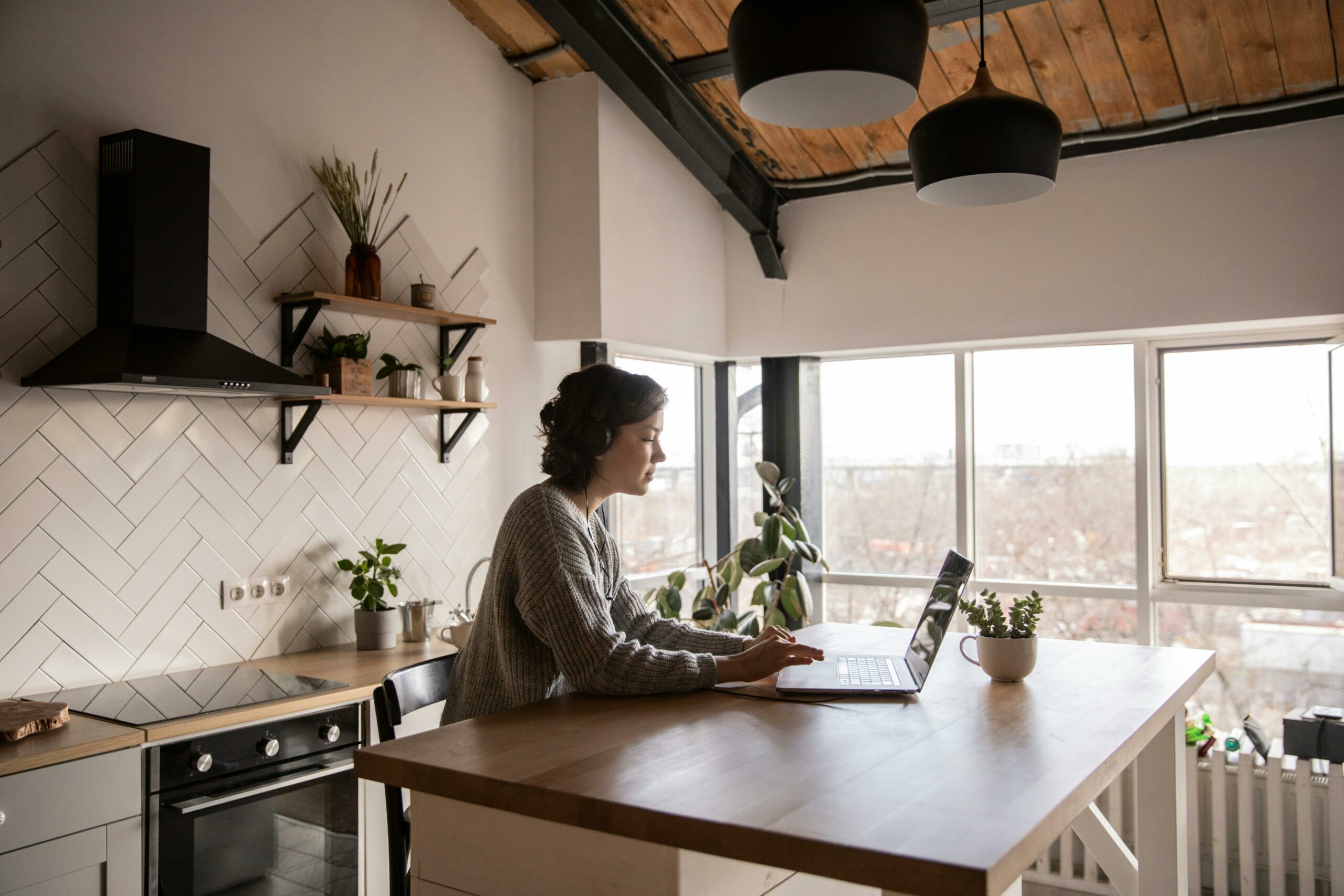A woman is in her kitchen and is doing mobile learning on her laptop