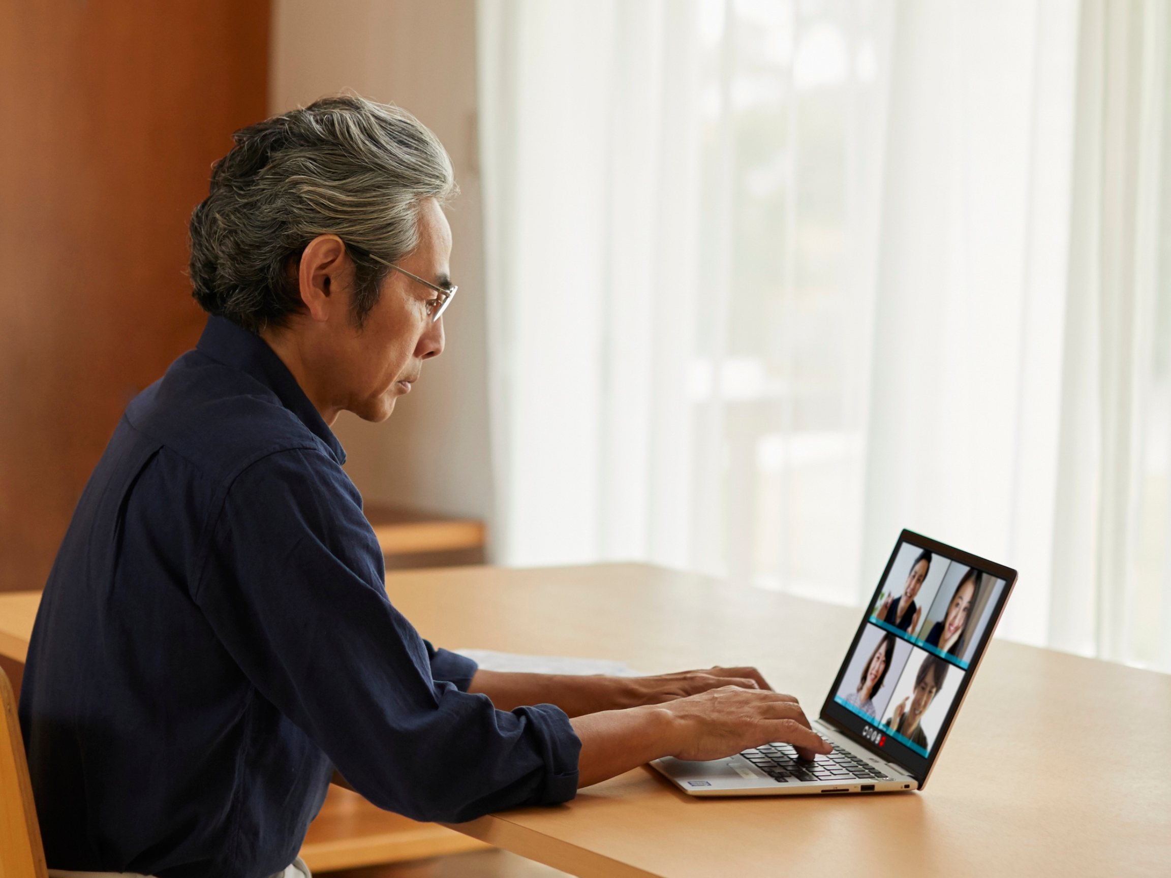 A man is on his laptop and is participating in a webinar as a featured guest and media partner of an association.