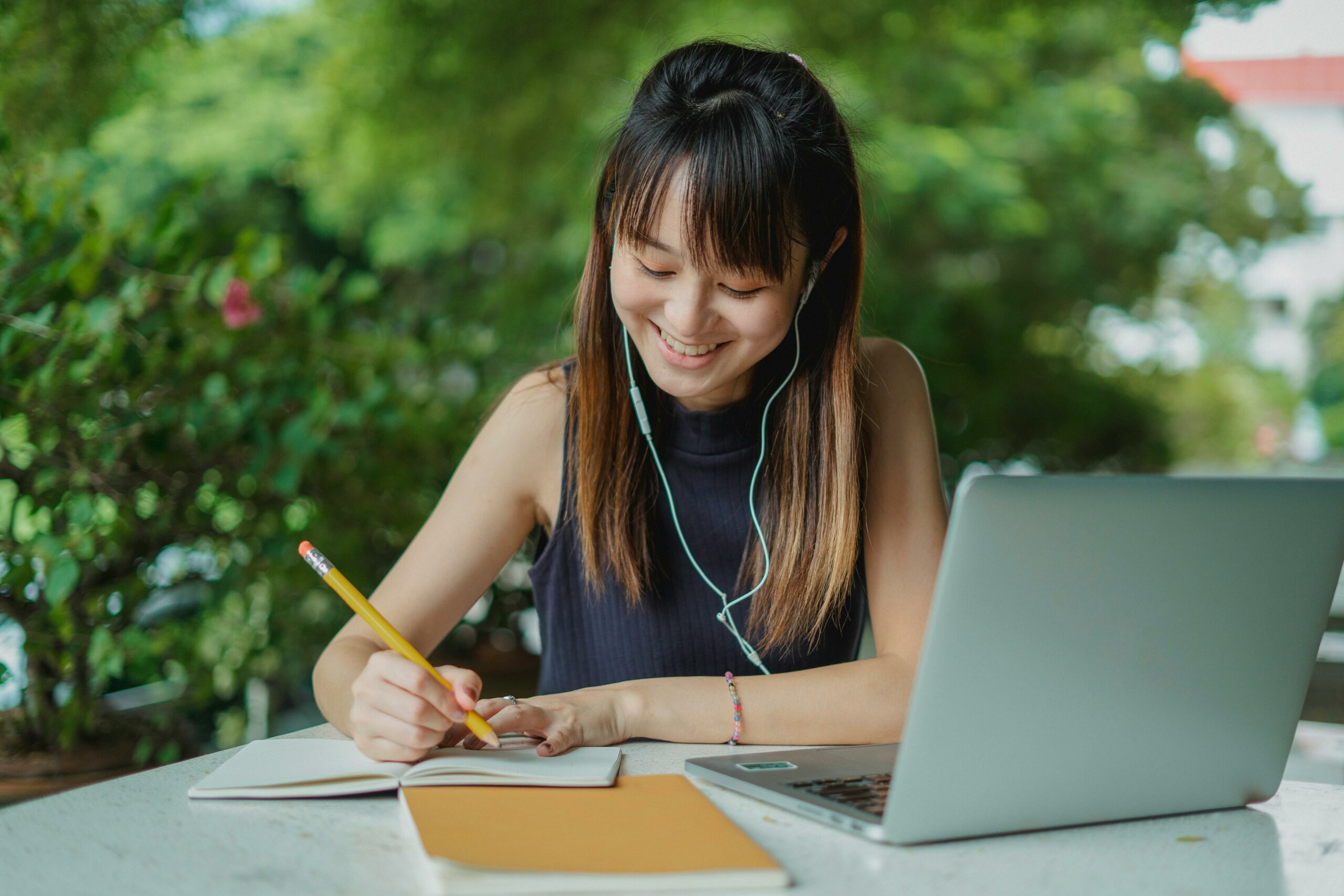 A woman is writing in front of her laptop and planning for thematic content structure
