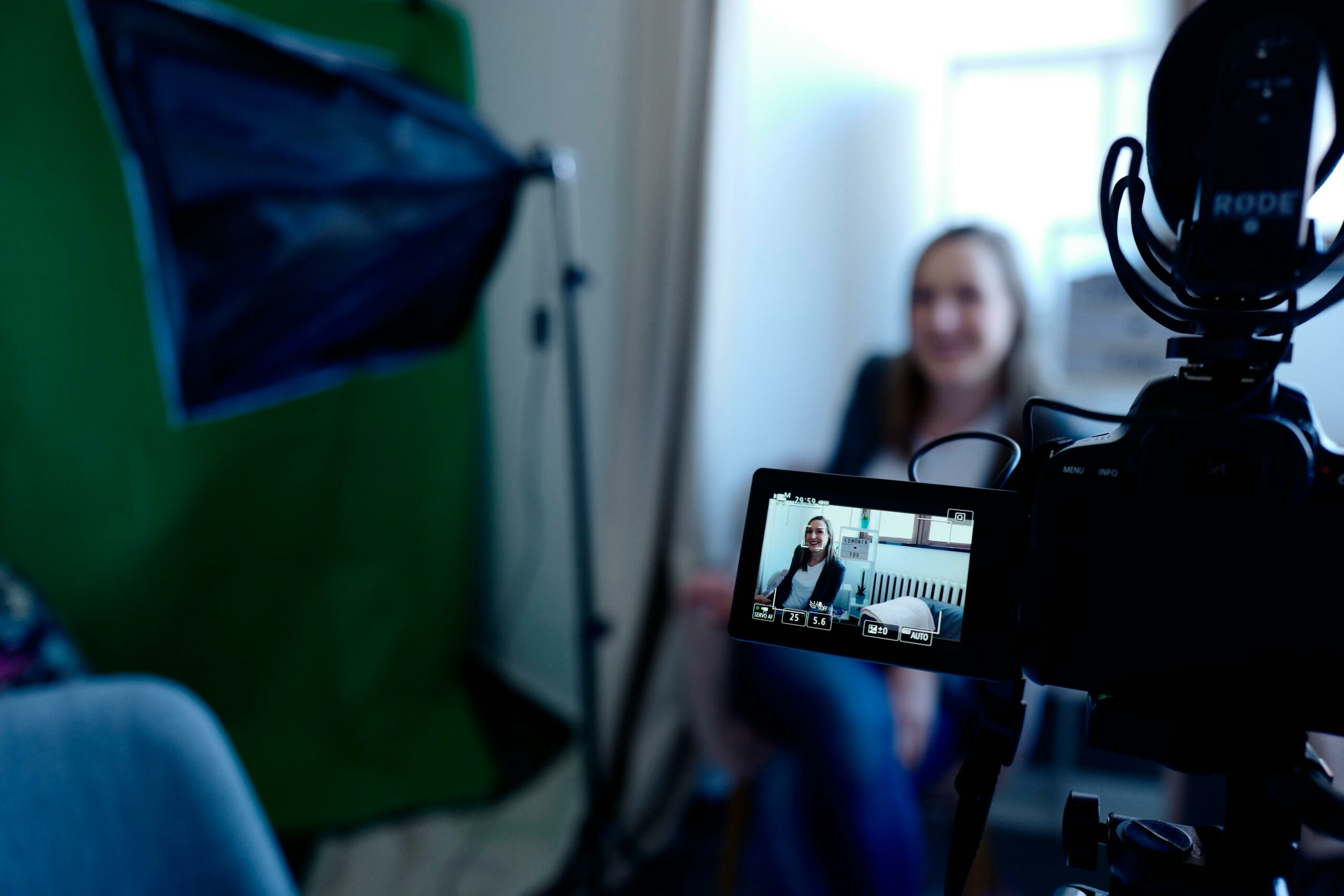 A shoot for an event promo video is done with a woman sitting on a chair and talking about why the viewers should not miss the event. This video material will be used fro promotional content.
