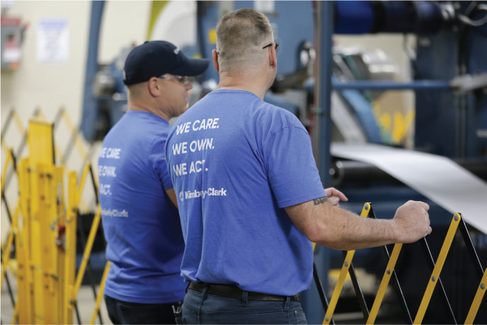 kimberly clark employees chat behind a safety barrier at the x mill