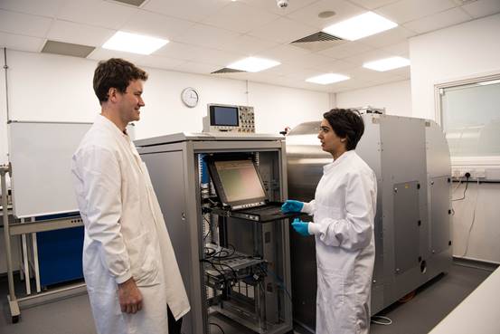 Los investigadores se ubican frente a un prototipo parcialmente completado de una máquina de almacenamiento de datos de ADN en Boston.