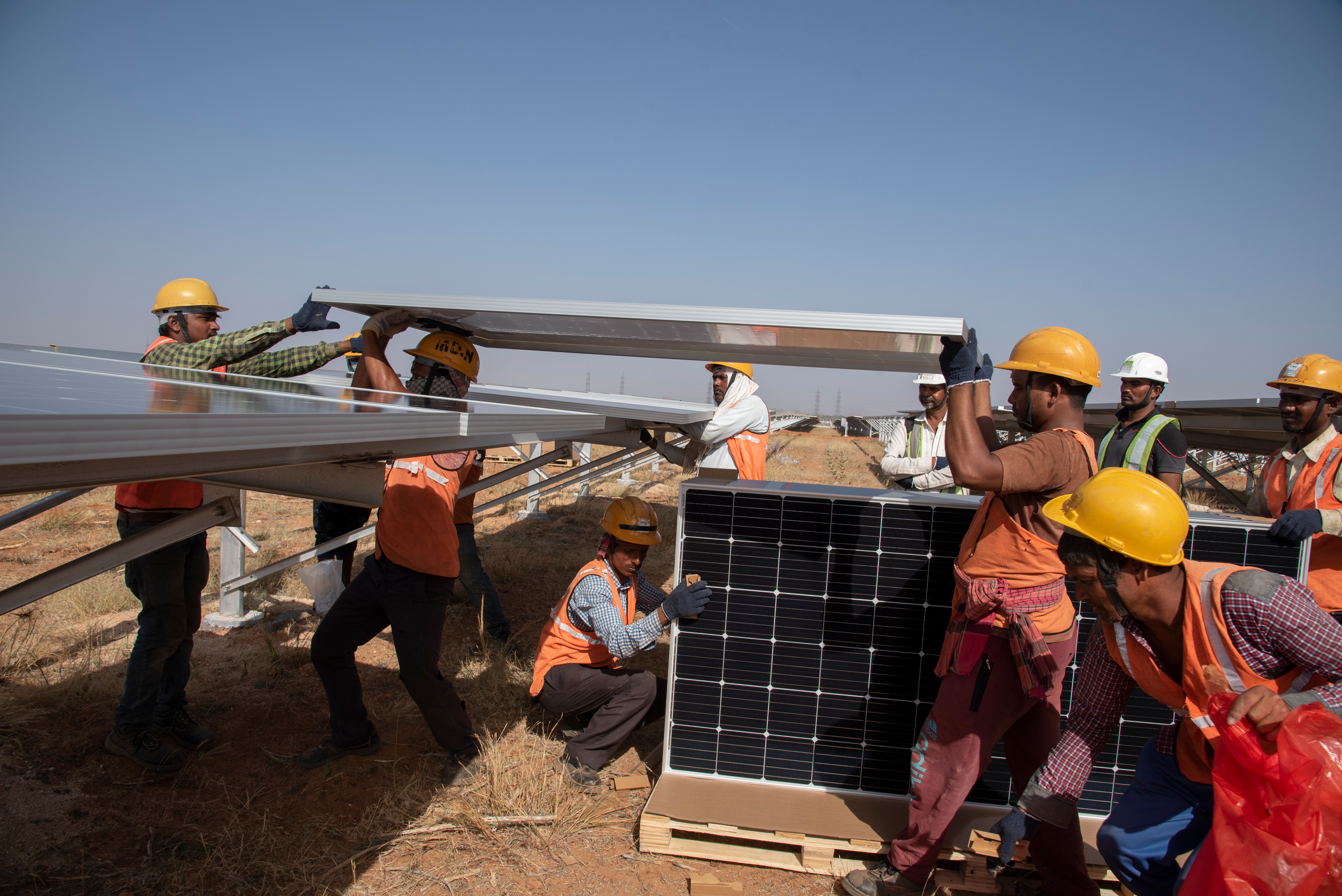 Los trabajadores del Parque Solar Pavagada colocan paneles en los estantes de ReNew Power