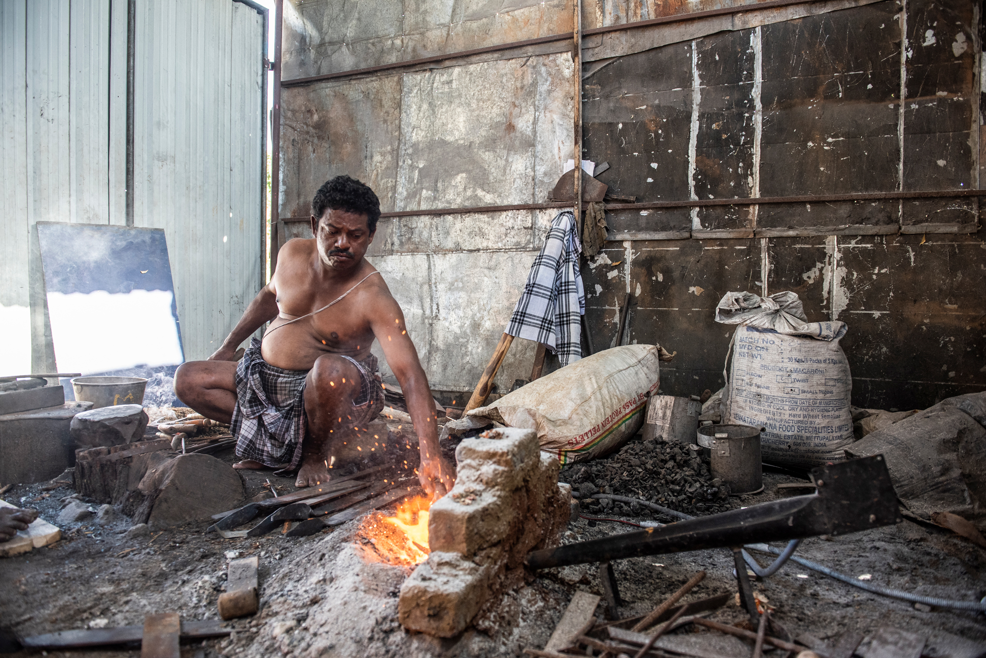 Sidhappa Ji, un herrero en Halaguru, golpea las vigas de metal en las hoces, usando un soplador de energía solar provisto por Selco para avivar el fuego.