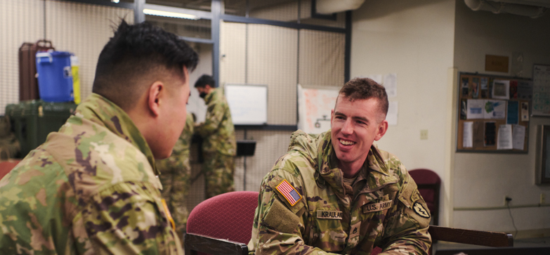 adam sits with a colleague in conversation