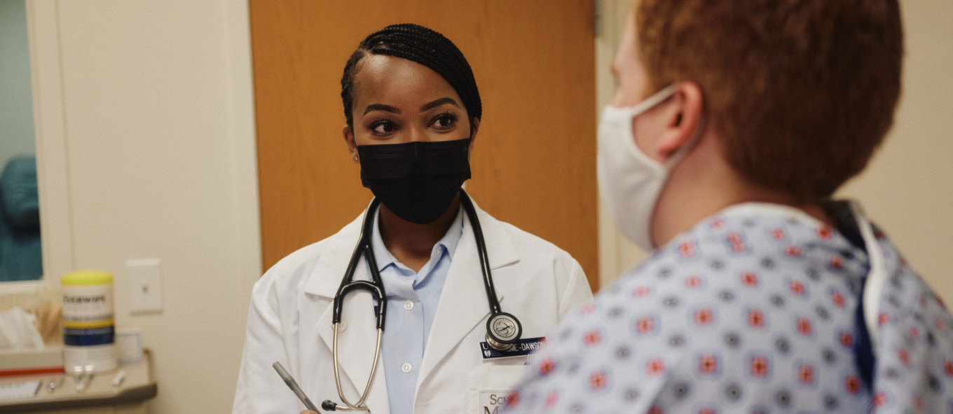 Brittany adminsters an exam while wearing a medical mask
