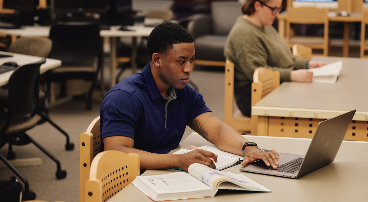 Isaac types at his computer while studying in the library