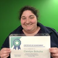 Woman smiling and holding certificate of achievement