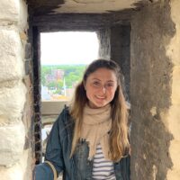 Image of woman with long, blond hair standing in front of an open window