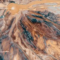 Arial of water pouring onto landscape of brown, black, white to cause rivulets