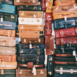 30+ suitcases piled on one another, variety of sizes and colors
