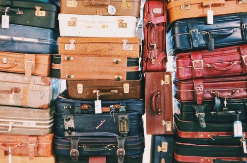 30+ suitcases piled on one another, variety of sizes and colors